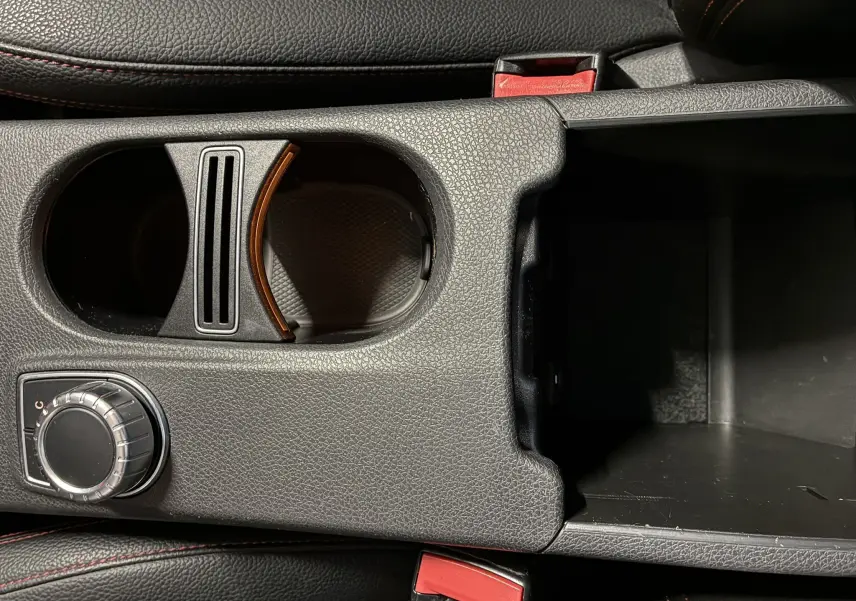 Gros plan sur la console centrale noire de la Mercedes Classe A 250 AMG Sport avec porte-gobelets et molette de réglage.
