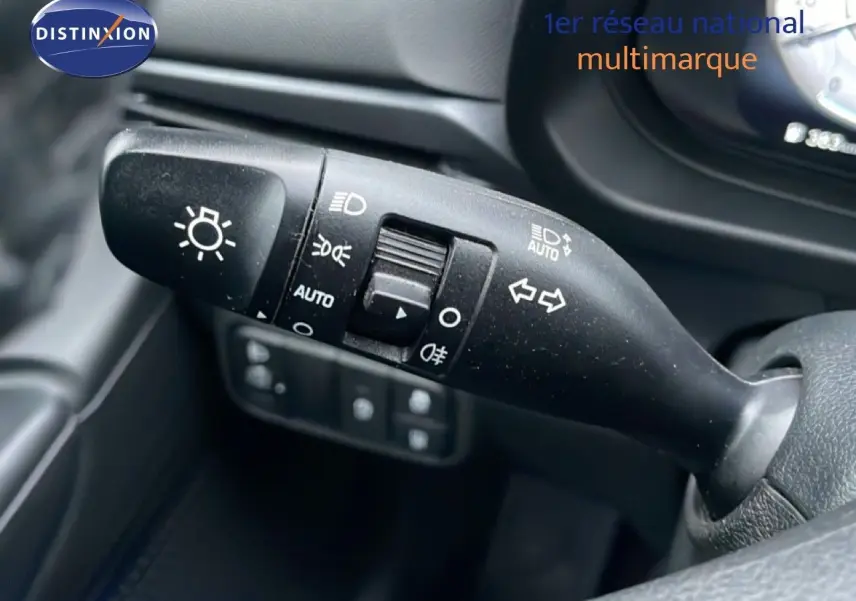 Gros plan sur la commande des feux et clignotants dans l'habitacle noir d'une Hyundai i20 rouge Dragon Metal 2025.