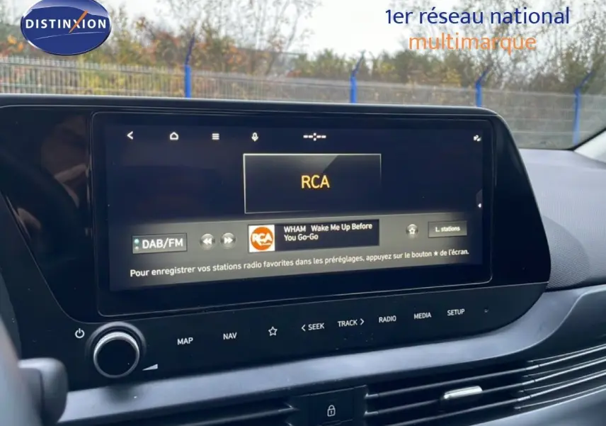 Écran tactile central du tableau de bord de la Hyundai i20 2025 affichant la radio DAB/FM en intérieur noir.