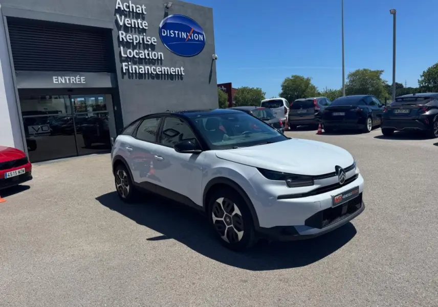 Citroën C4 hybride blanc vue 3/4 avant droit, avec toit noir et jantes alliage 18 pouces, stationnée devant un showroom.