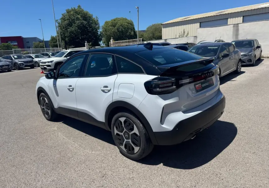 Vue 3/4 arrière droite d'une Citroën C4 hybride blanche avec toit noir et jantes alliage 18 pouces.