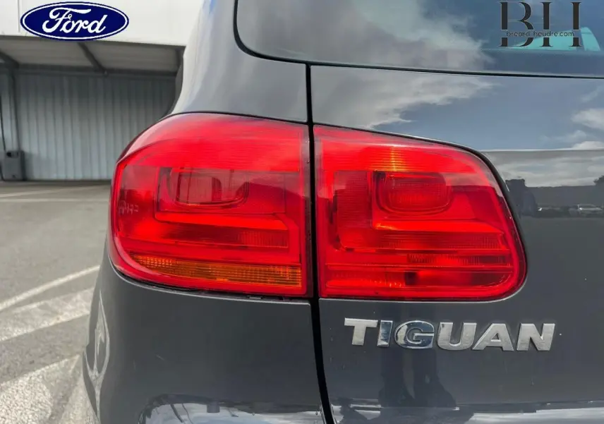 Gros plan sur le feu arrière gauche d’un Volkswagen Tiguan gris poivre avec le logo Tiguan visible sur le hayon.