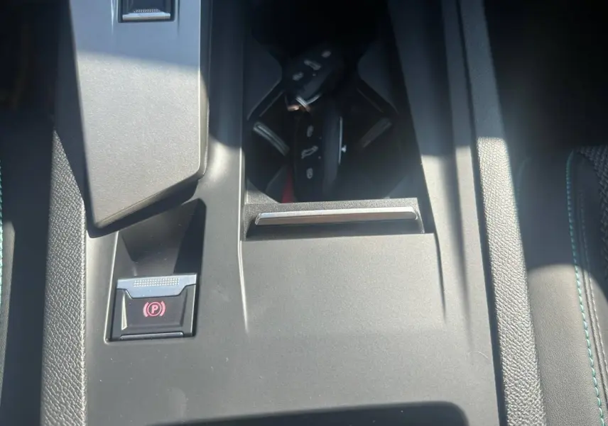 Gros plan sur la console centrale de la Peugeot 308 SW blanche, avec frein à main électrique et porte-clés visible.