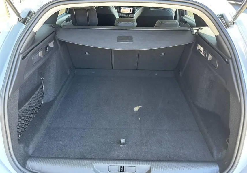 Vue intérieure du coffre spacieux et propre de la Peugeot 308 SW blanc Okénite, avec cache-bagages déployé.