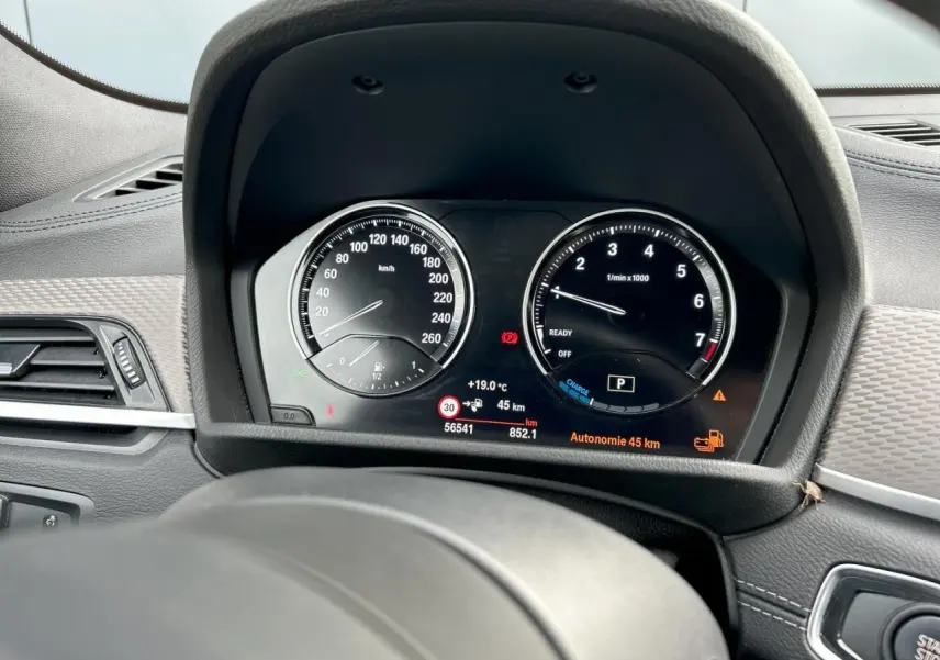 Vue rapprochée du tableau de bord noir du BMW X2 F39 avec compteurs analogiques et affichage digital clair.