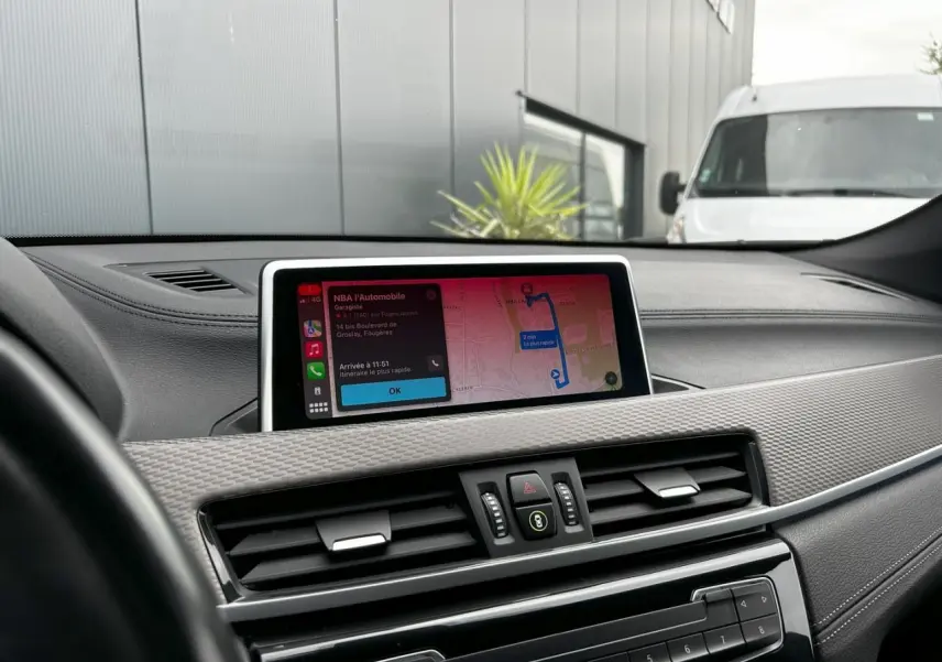Vue rapprochée du tableau de bord de la BMW X2 F39, avec écran GPS affichant un itinéraire et détails de navigation.