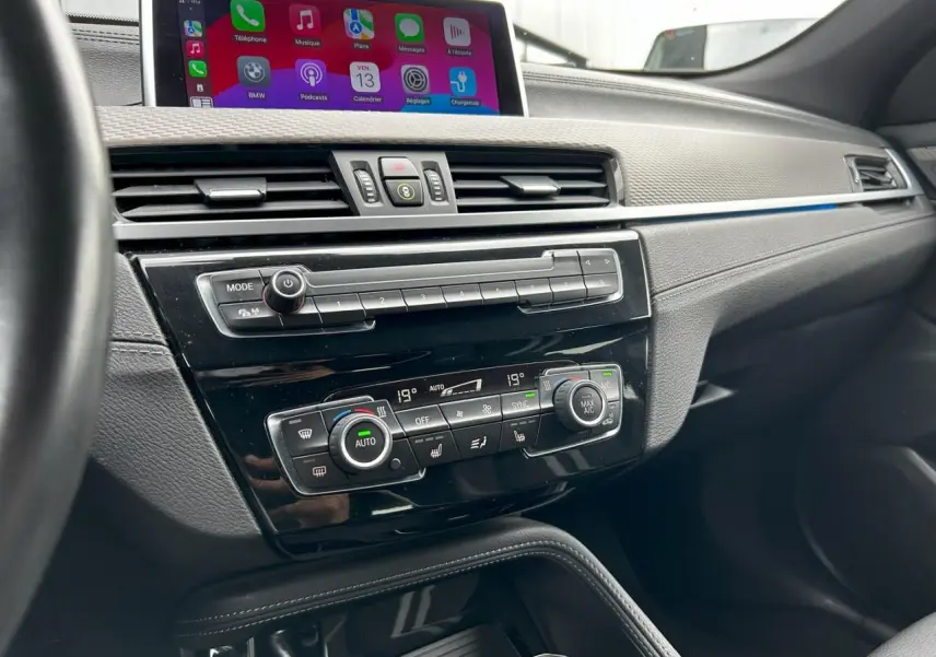 Vue rapprochée de la console centrale du BMW X2 F39 avec écran tactile et commandes de climatisation automatique.