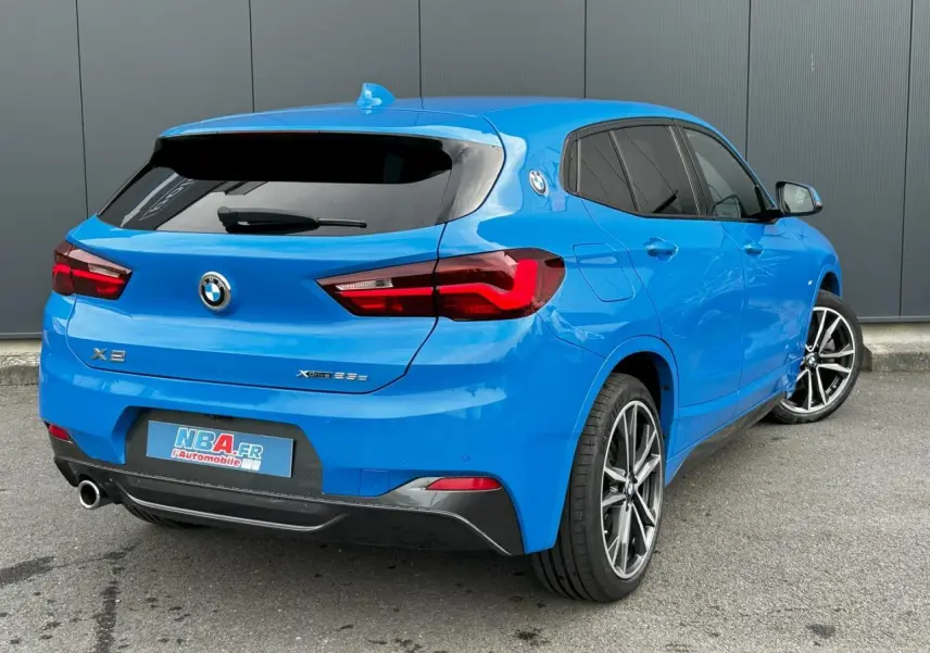 BMW X2 bleu Misano vue 3/4 arrière droit avec jantes alliage bicolores et vitres teintées