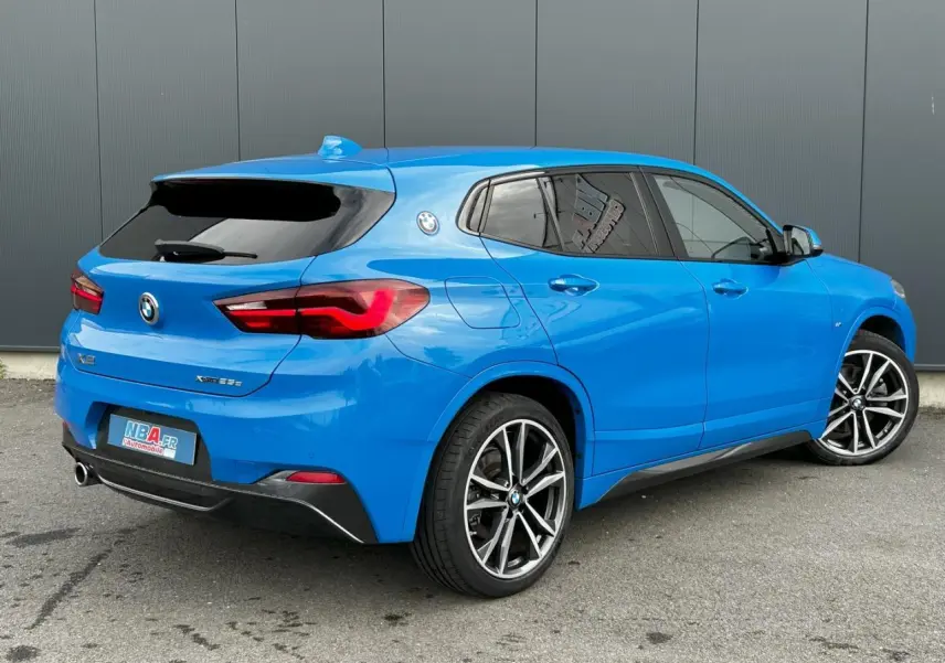 BMW X2 F39 xDrive 25e bleu Misano vue 3/4 arrière côté droit avec jantes alliage bicolores et vitres teintées
