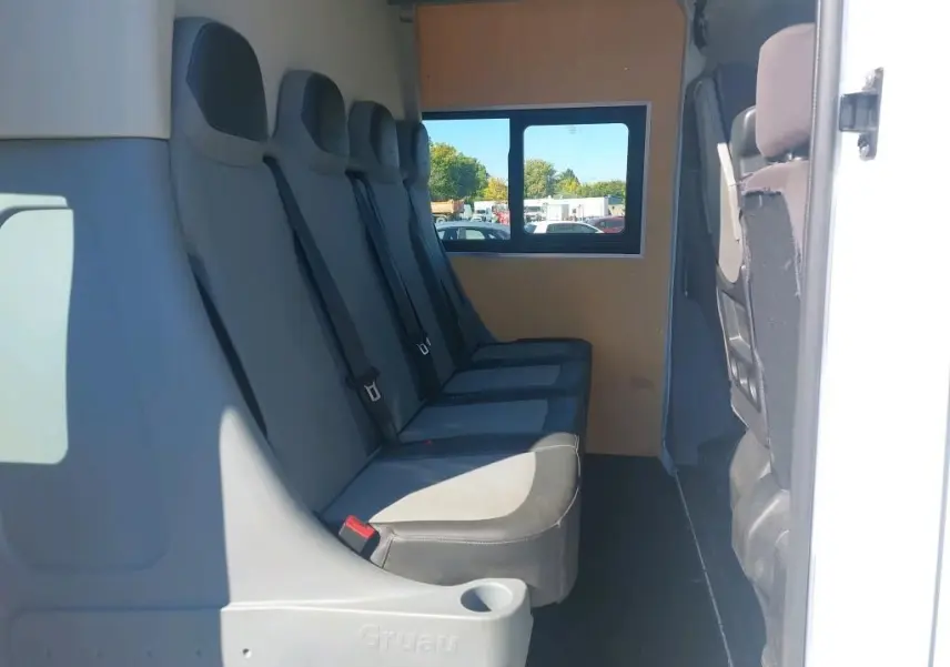 Vue intérieure latérale droite des sièges gris du Renault Master Cabine Approfondie blanc, version 7 places avec fenêtre arrière.