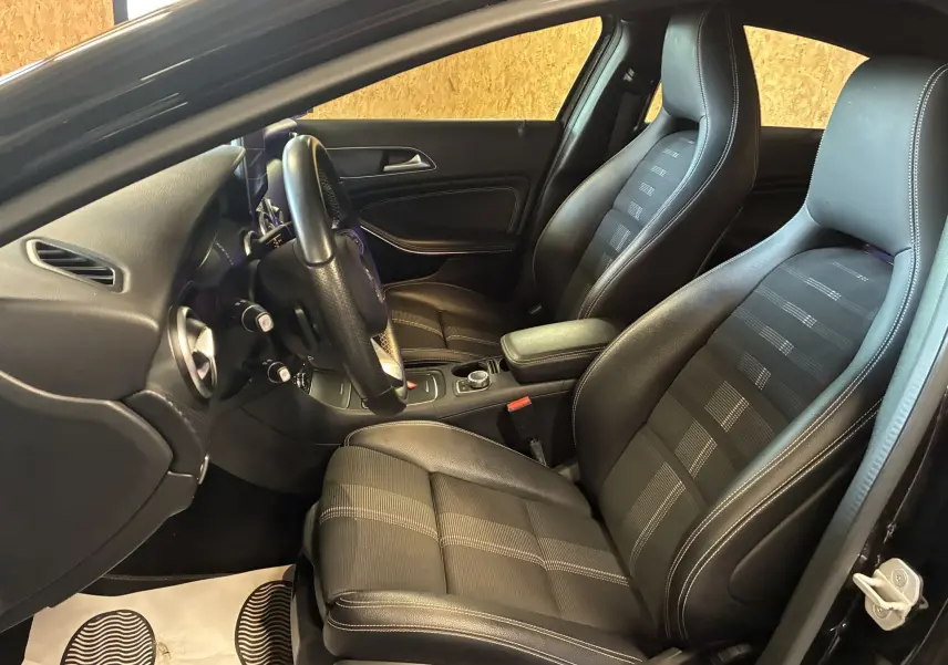 Vue intérieure côté conducteur de la Mercedes Classe A 180 CDI Sensation noire, sièges sport en cuir noir avec surpiqûres blanches.