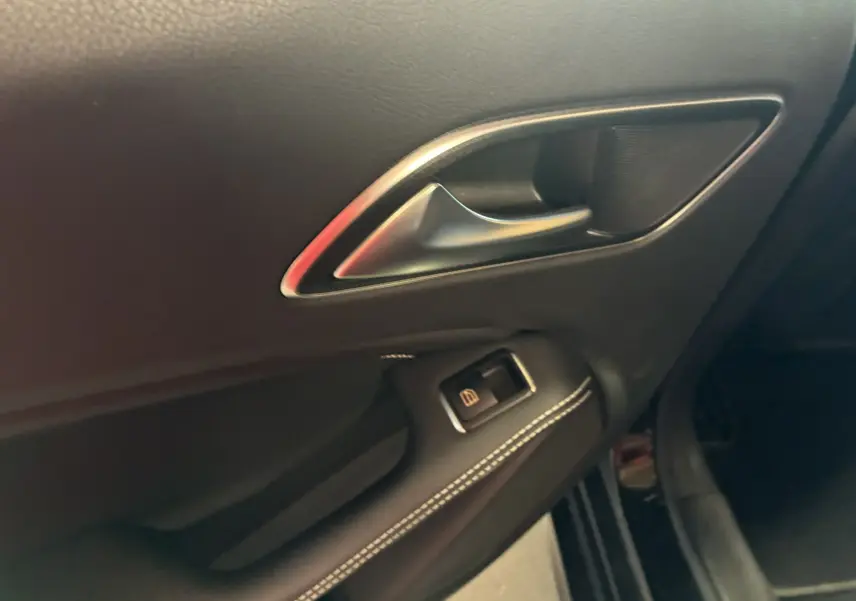 Poignée de porte intérieure côté gauche en cuir noir avec surpiqûres blanches sur une Mercedes Classe A 180 CDI Sensation 2018.