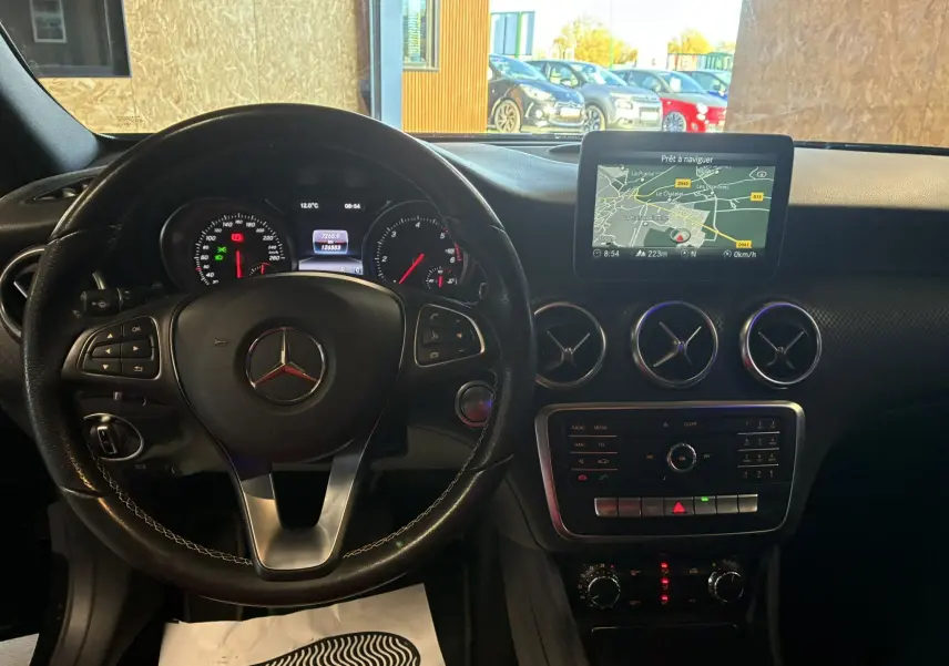 Vue intérieure du tableau de bord et volant noir d'une Mercedes Classe A 180 CDI Sensation avec écran GPS et aérateurs ronds chromés.