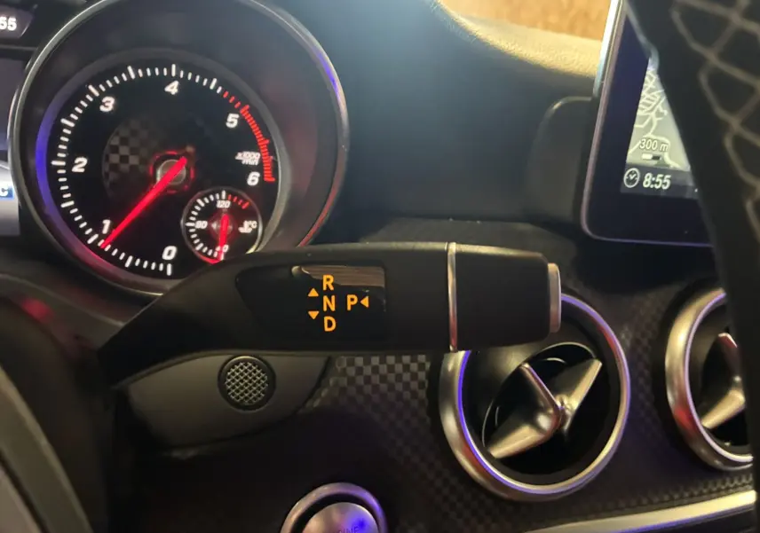 Gros plan sur la commande de boîte automatique avec affichage des vitesses, tableau de bord et aérateurs du Mercedes Classe A noir 2018.