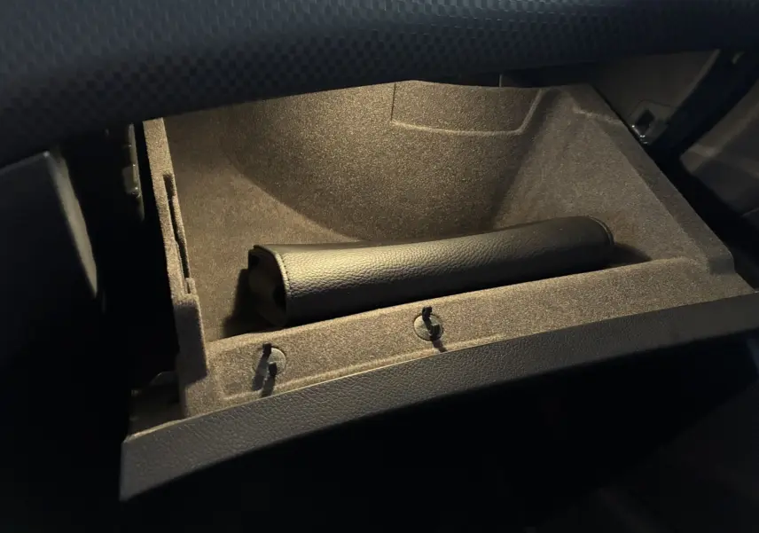 Gros plan sur la boîte à gants ouverte en tissu noir avec un étui en cuir noir dans une Mercedes Classe A 180 CDI Sensation 2018.