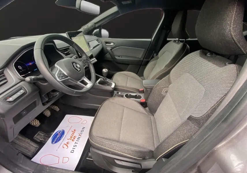 Vue intérieure côté conducteur du Renault Captur 2025 avec sièges tissu gris et tableau de bord moderne.