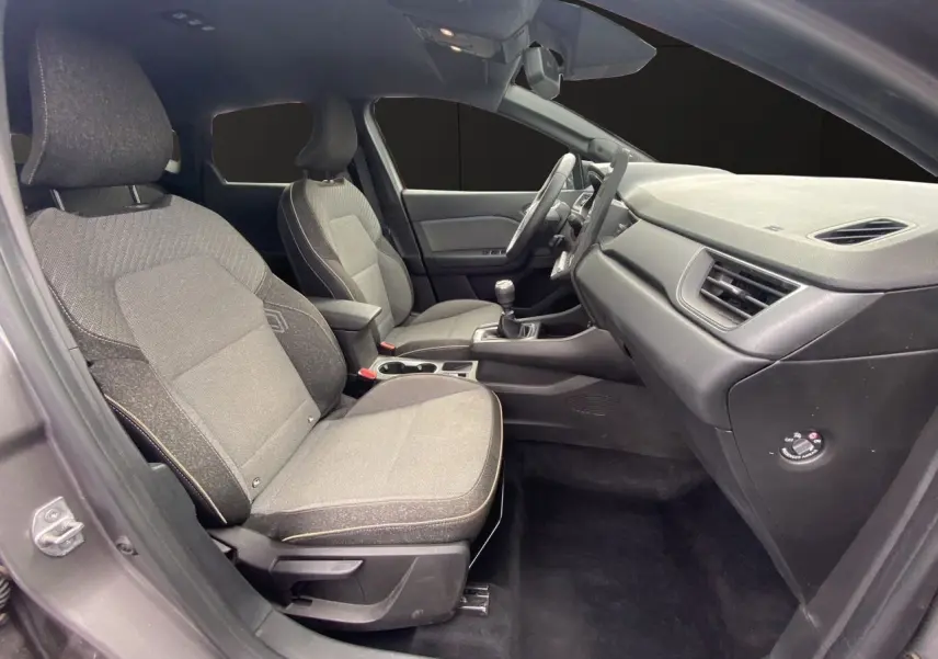 Vue intérieure côté conducteur du Renault Captur 2025 avec sièges tissu gris et tableau de bord noir.