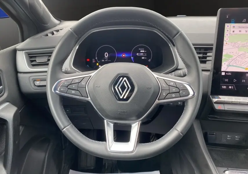 Vue intérieure centrée sur le volant noir de la Renault Captur 2025 avec tableau de bord digital et écran tactile GPS.