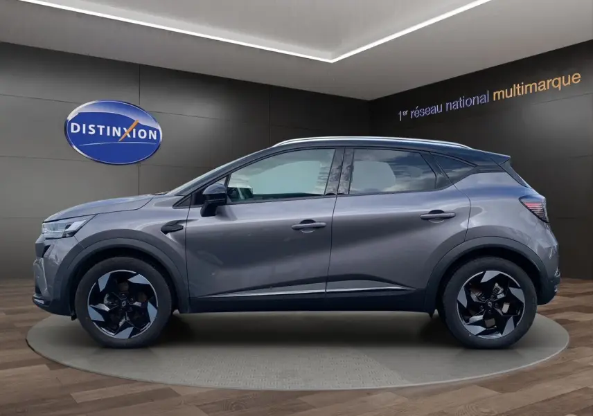 Profil côté gauche du Renault Captur gris Cassiopée avec toit noir, jantes alu 18 pouces et barres de toit visibles.