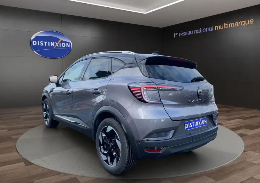 Vue 3/4 arrière droite du Renault Captur gris Cassiopée avec toit noir et jantes alu 18 pouces, barres de toit visibles.