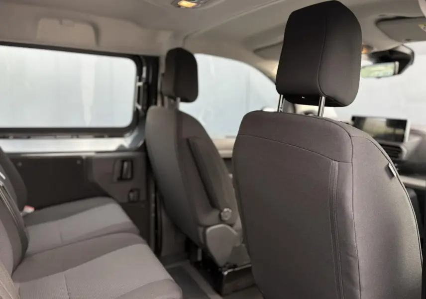 Vue intérieure côté droit du Citroën Jumpy XL 2025, montrant les sièges tissu bi-ton noir et gris et la banquette arrière.