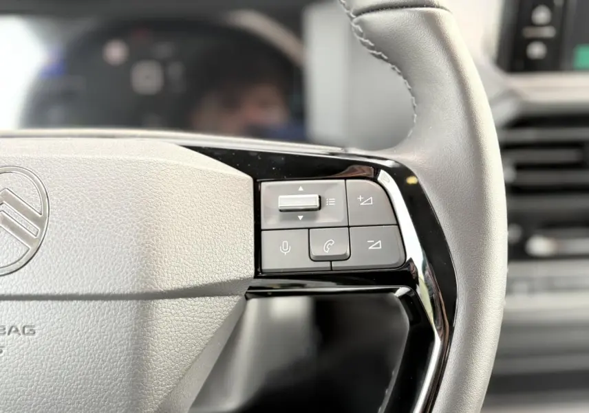 Gros plan sur les commandes du volant cuir gris du Citroën Jumpy XL 2025, avec boutons multifonctions noirs.