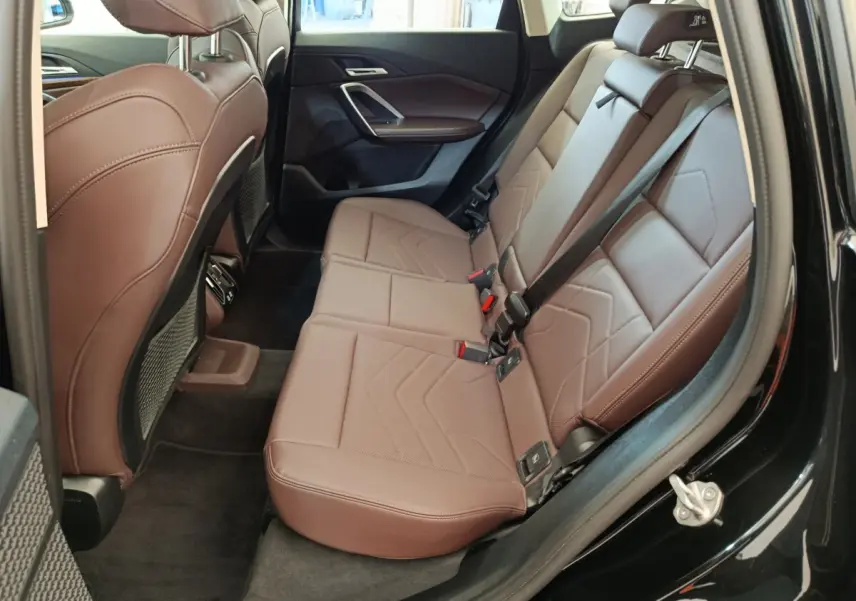 Vue intérieure arrière côté droit montrant la banquette marron en cuir du BMW X1 sDrive18i 2023 noir.