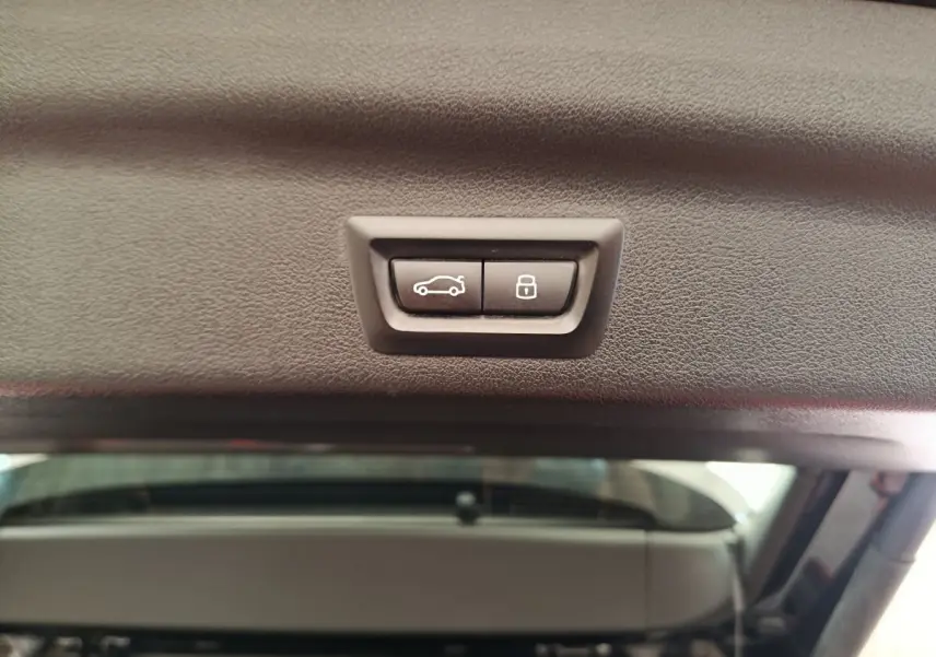Boutons de fermeture et verrouillage électrique du coffre vus de l'intérieur du hayon d'un BMW X1 noir 2023.