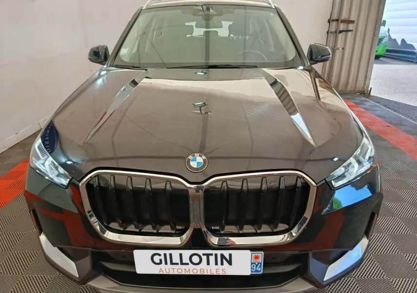 Vue avant d’un BMW X1 noir 2023 avec calandre imposante et phares LED dans un garage.