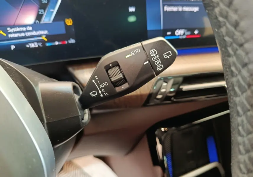 Gros plan sur la commande d’essuie-glace à gauche du volant dans l’habitacle d’une BMW X1 noire 2023.