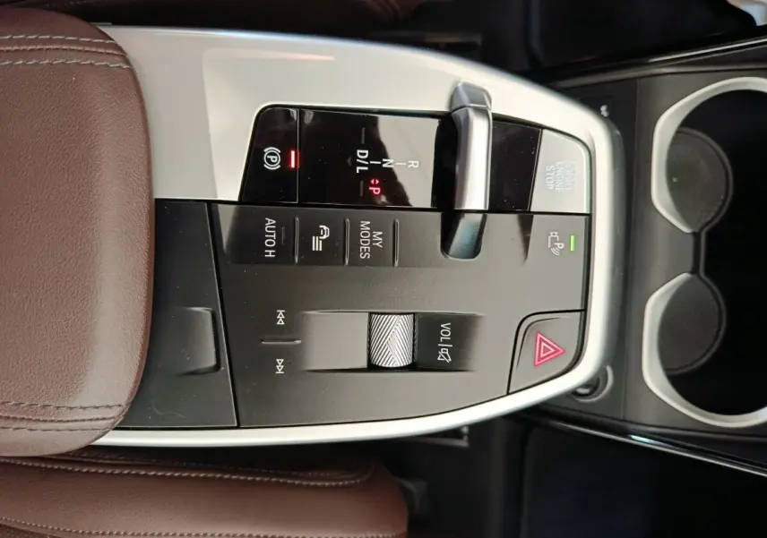 Vue rapprochée de la console centrale du BMW X1 2023, avec levier de boîte auto et accoudoir cuir marron.