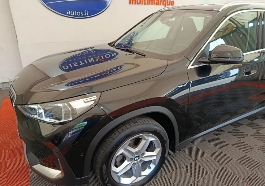 BMW X1 sDrive18i noir vue 3/4 avant droit, mettant en valeur les phares LED et la jante alliage.