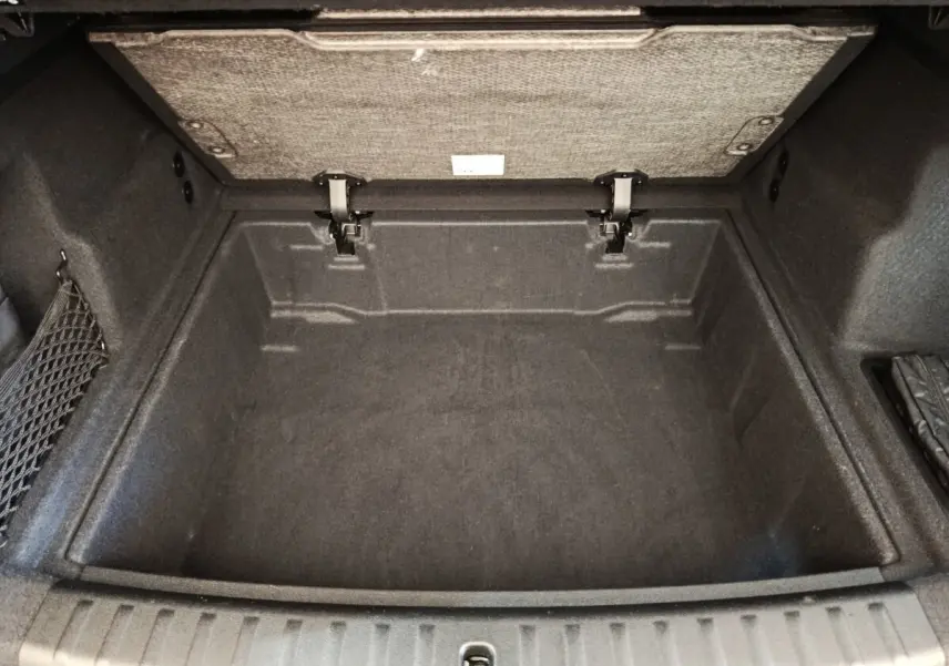 Coffre ouvert vu de dessus d’un BMW X1 noir 2023, espace de rangement profond avec revêtement textile gris foncé.