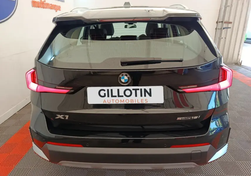 Vue arrière d’un BMW X1 noir 2023 avec feux LED allumés et logo visible sur coffre fermé.