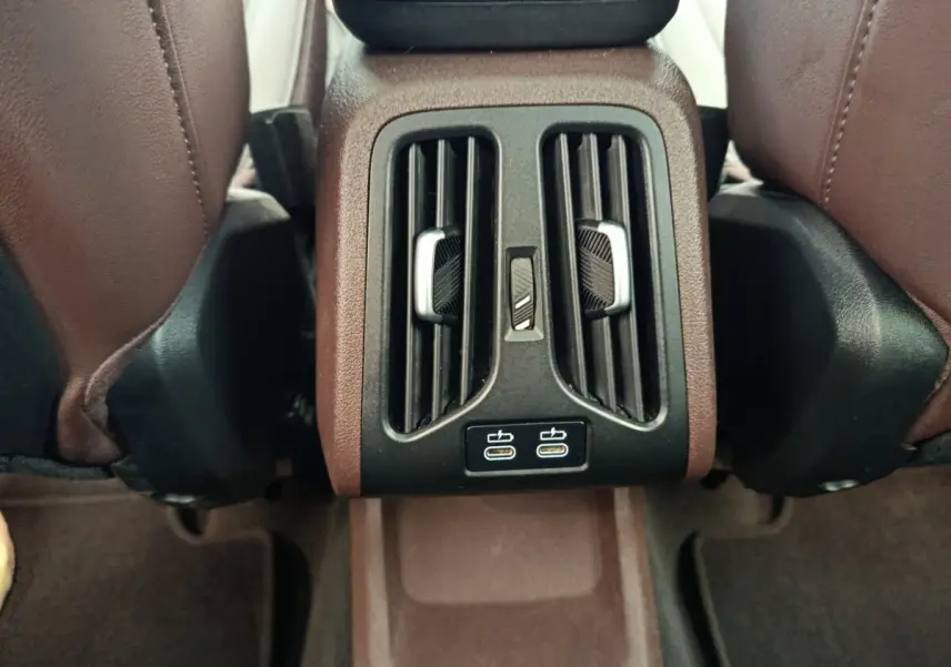 Vue rapprochée des aérateurs arrière et ports USB-C noirs au centre entre les sièges marron du BMW X1 2023.