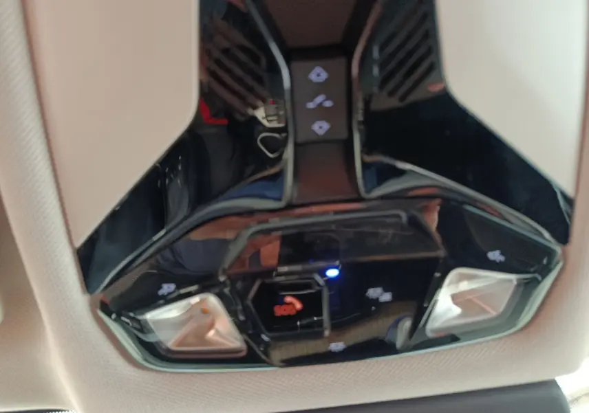 Gros plan sur le plafonnier noir brillant de la BMW X1 2023 avec commandes d’éclairage et bouton SOS.