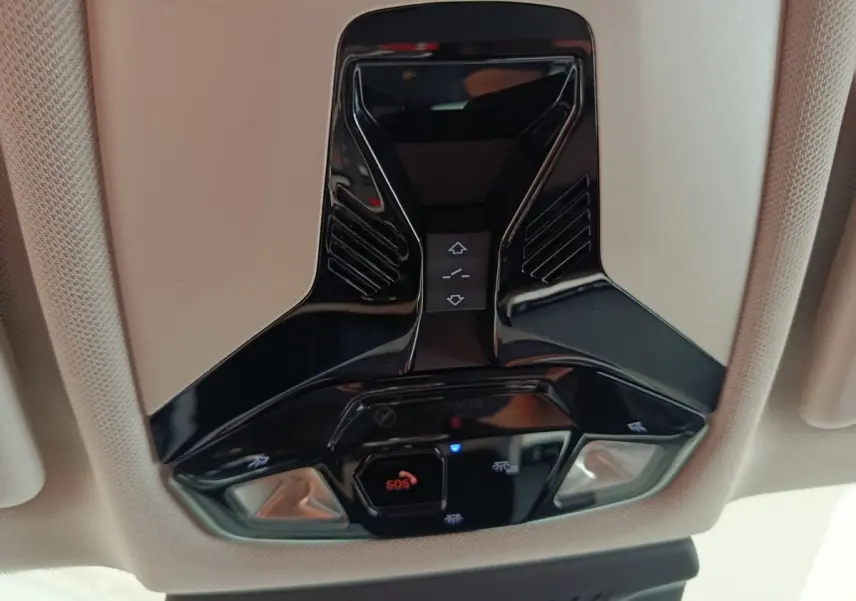 Vue en gros plan du plafonnier noir brillant avec commandes d'éclairage et bouton SOS dans un BMW X1 noir 2023.