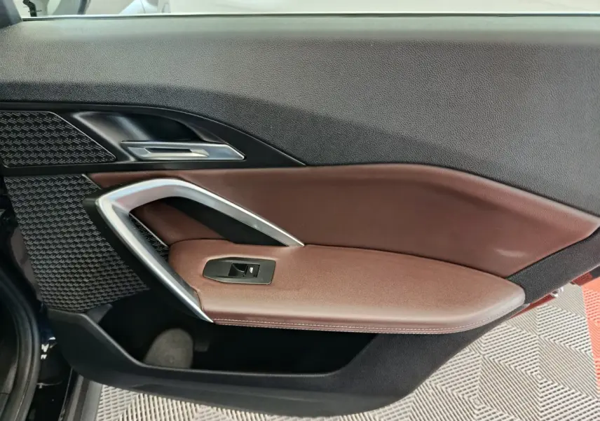 Gros plan sur la porte intérieure côté gauche de la BMW X1 2023, avec garniture marron et insert argenté.
