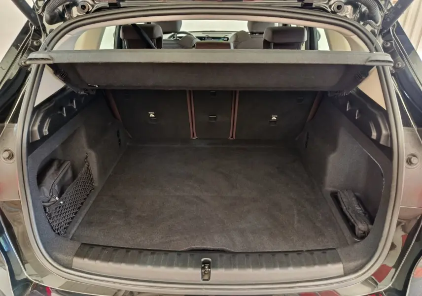 Coffre ouvert vu de l'arrière d'un BMW X1 noir 2023, espace de chargement propre et bien agencé.