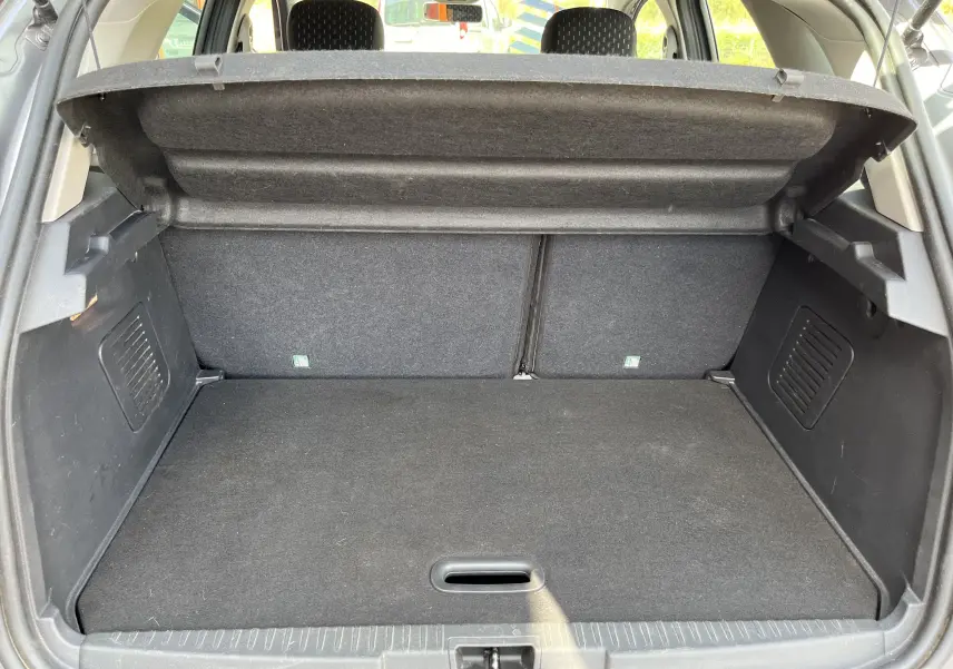 Coffre ouvert d'un Renault Captur gris 2019, vue arrière montrant l'espace de chargement et la plage arrière relevée.