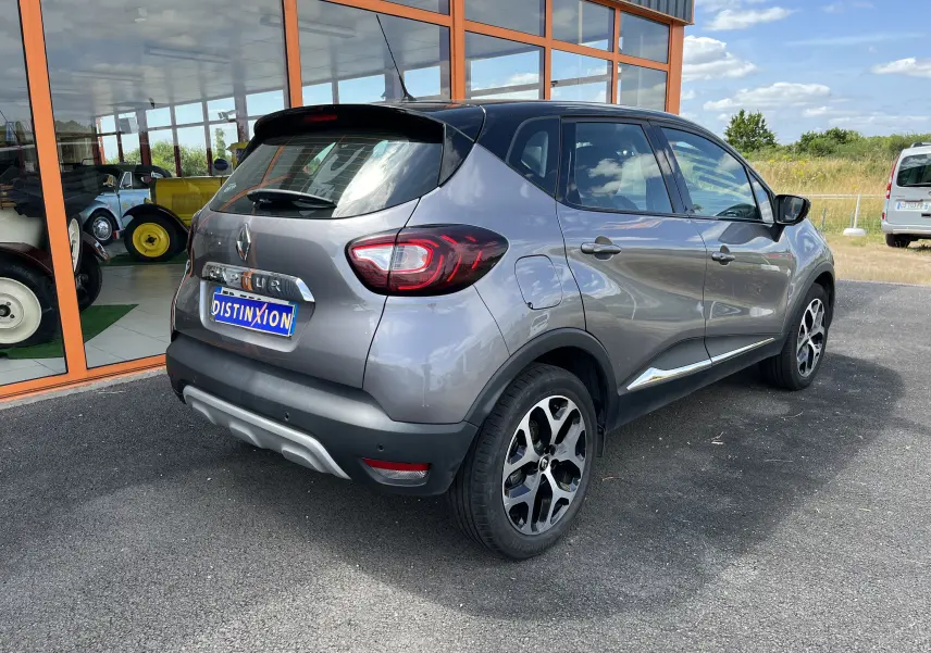 Renault Captur gris en vue 3/4 arrière droit, avec jantes alliage et feux arrière LED distinctifs.