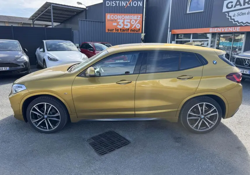 Profil côté gauche d'un BMW X2 jaune métallisé sDrive 18d M Sport avec jantes alliage 19 pouces et toit panoramique.