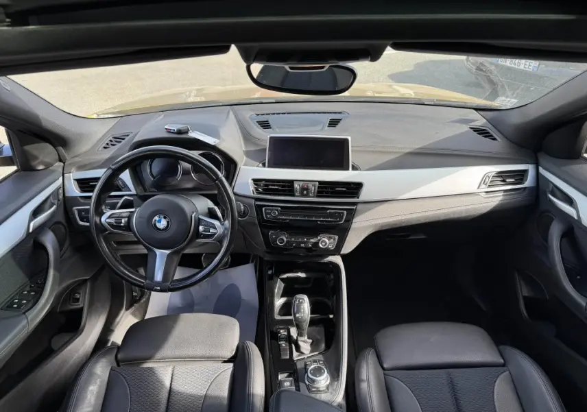 Vue intérieure avant du BMW X2 M Sport 2021, tableau de bord noir avec volant cuir M et écran central intégré.