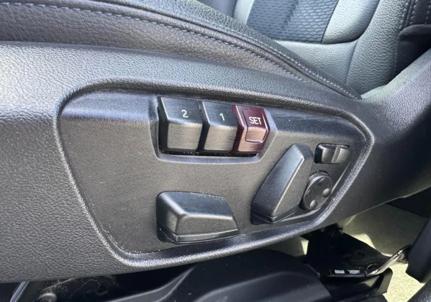 Gros plan sur les commandes électriques de réglage du siège conducteur noir du BMW X2 sDrive 18d M Sport 2021.