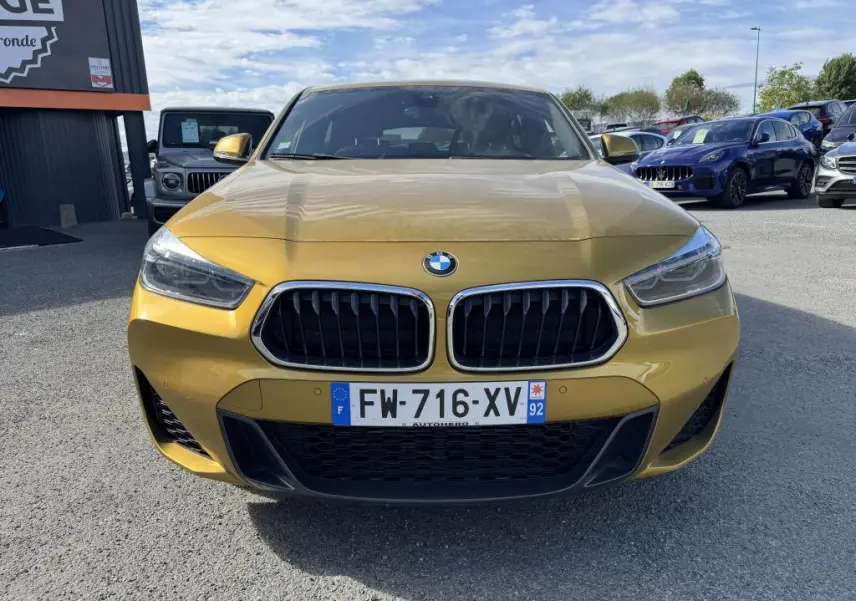 Vue frontale d'une BMW X2 jaune métallisée avec calandre noire et plaques d'immatriculation françaises.