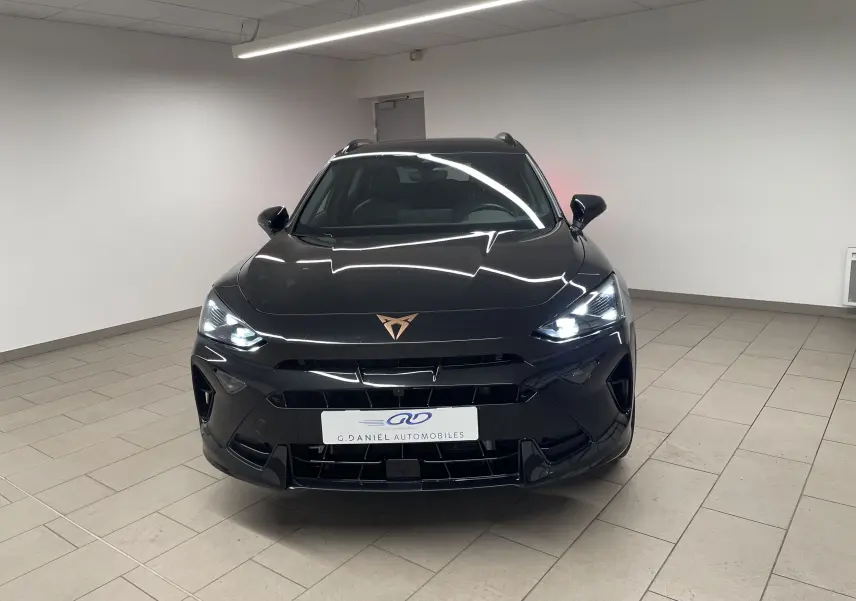 Vue frontale d'un CUPRA Formentor noir minuit avec phares allumés dans un showroom lumineux.
