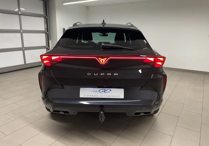 Vue arrière d'un CUPRA Formentor noir minuit avec feux LED allumés et crochet d'attelage escamotable visible.