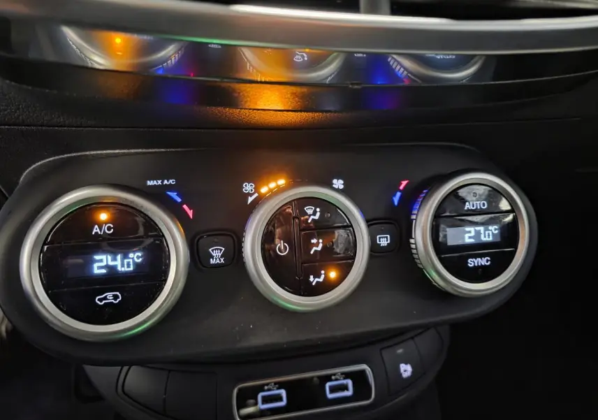 Gros plan sur la commande de climatisation bi-zone avec affichage digital et réglages sur Fiat 500X gris 2024.