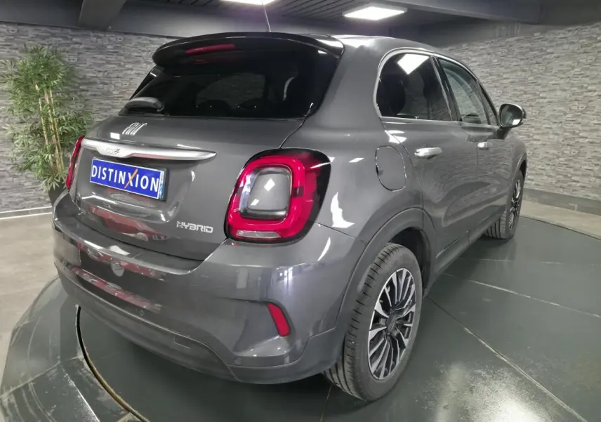 Vue 3/4 arrière droite du Fiat 500X gris avec feux arrière LED et jantes alliage 17 pouces dans un showroom.