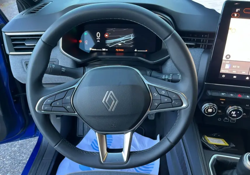 Vue rapprochée du volant cuir multifonctions et du tableau de bord numérique de la Renault Clio Bleu Iron 2025.